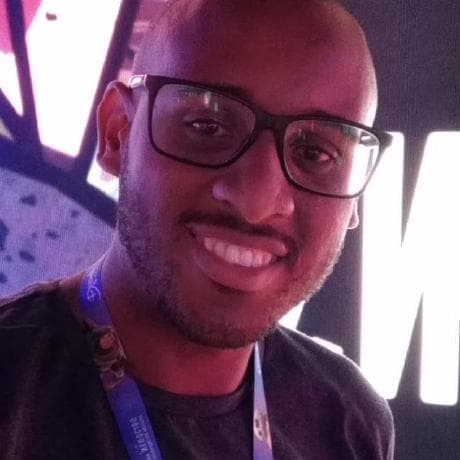 Foto de Junior Marques, usando óculos preto e sorrindo.